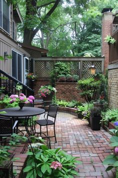 an outdoor patio with tables and chairs surrounded by trees, bushes and flowers in pots