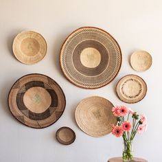 the wall is decorated with woven baskets and flowers in vases on top of a table