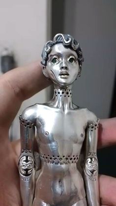 a silver statue is being held up by someone's finger in the middle of their hand