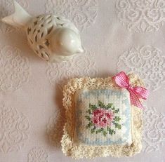 a cross - stitched pillow with a fish on it next to a ceramic figurine