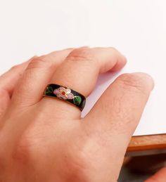 a person's hand with a ring on top of their finger next to a pen