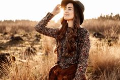 a woman wearing a hat and dress standing in a field