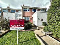 a red auction sign sitting in front of a house