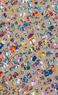 an aerial view of people on the beach with umbrellas, chairs and other items