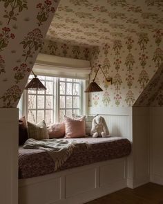 a window seat in the corner of a room with floral wallpaper on the walls