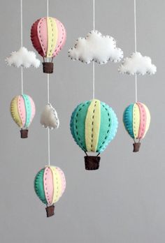 a mobile with hot air balloons hanging from it's sides and clouds in the background