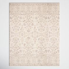 a beige and white rug with an intricate design on the bottom, in front of a wall