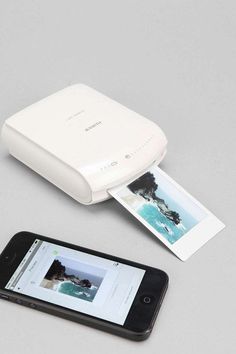 a cell phone sitting next to an instant photo printer