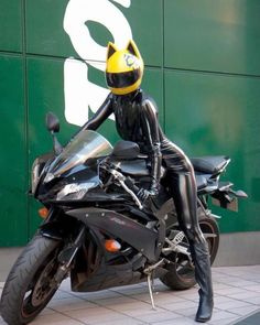 a woman in black catsuit sitting on a motorcycle