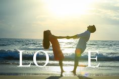 two people holding hands on the beach with the word love written in front of them