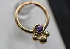 Amethyst  seamless ring  with beads 14k solid Gold (NOT plated or filled)  Choose Yellow Gold, Rose Gold or White Gold and your size ring. - Perfect for Septum's or Daith's  Put in notes if you would like 16G or 18G   WHAT'S THE DIFFERENCE IN GOLD COLORS? The three different gold colors are the perfect array. The yellow gold is just the right hue, an instant classic and must have in any collection. Rose gold is a soft pink with the classic gold undertones. White gold is subtle and familiar. Handmade and sold individually.  NOTE: In stock items ship immediately! Backordered and custom items ship in 3-5 days. Made from nickel free 14k solid gold If you have any questions, please let us know! Stackable Amethyst Gold Jewelry, Gold Stackable Amethyst Ring, Piercing Studio, Septum Jewelry, Gold Colors, Nose Rings, Nose Ring Stud, Classic Gold, Body Jewellery