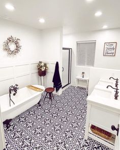 a white bathroom with black and white tile flooring on the walls, sink, toilet and bathtub