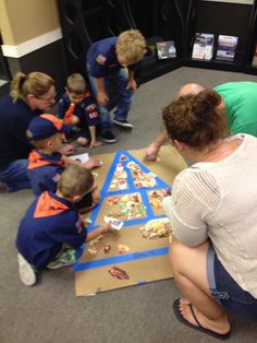 a group of people sitting on the floor around a table with cake in front of them