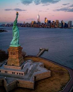 an aerial view of the statue of liberty in new york city, ny at sunset