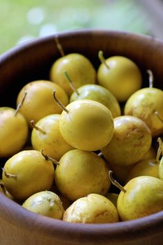 a wooden bowl filled with lots of yellow fruit