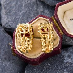 These elegant earrings feature east-to-west set emerald cut garnets set atop woven gold that gracefully curves beneath the bottom of the ear. They are crafted in 14k yellow gold and are finished with posts and omega backs for pierced ears. Gold Gemstone Clip-on Earrings For Anniversary, Diamond Yellow Gold Clip-on Earrings Gift, Yellow Gold Clip-on Jewelry For Gift, Gold Gemstone Clip-on Earrings For Formal Occasions, Yellow Gold Clip-on Jewelry For Anniversary, Formal Gold Gemstone Clip-on Earrings, 14k Gold Baguette-cut Diamond Earrings For Formal Occasions, 14k Gold Clip-on Jewelry As Gift, Art Deco Ruby Jewelry For Formal Occasions