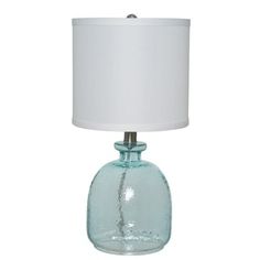 a blue glass table lamp with a white shade on the base and a light bulb attached to it