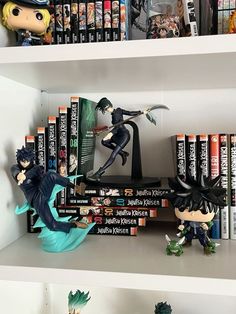 two anime figurines are on top of bookshelves in front of them