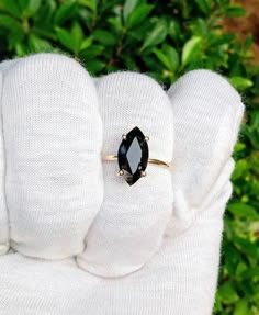 a woman's hand wearing a white glove with a black stone ring on it