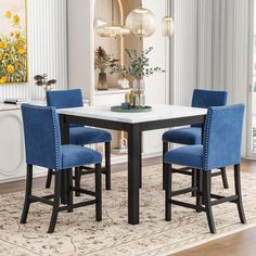 a dining room table with blue chairs and a rug on the floor in front of it