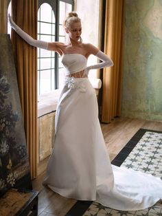 a woman in a white wedding dress is posing for the camera with her arms outstretched