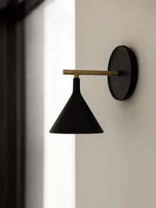 a black wall light mounted on the side of a white wall next to a window