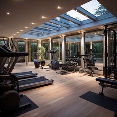 there are many exercise machines in this gym area with glass walls and skylights above them