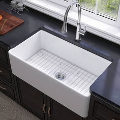 a white kitchen sink sitting under a window next to a cutting board and utensils