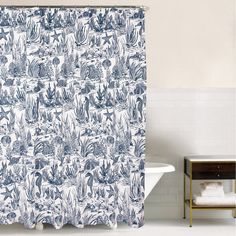 a blue and white shower curtain with an image of plants on it in the bathroom