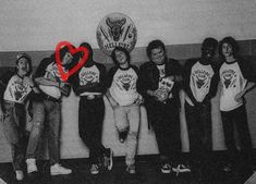 a group of young men standing next to each other in front of a red heart