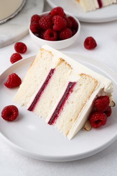 a slice of cake on a plate with raspberries and almonds around it