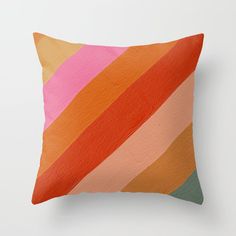 an orange and pink striped pillow on a white wall