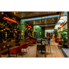 the interior of a restaurant with plants on the wall and chairs in front of it