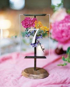 an image of flowers in a vase on top of a wooden stand with the letter f