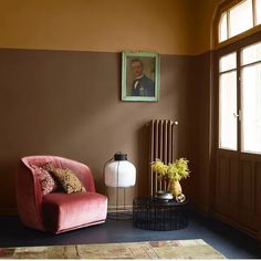 a living room with a red chair next to a painting on the wall and a lamp