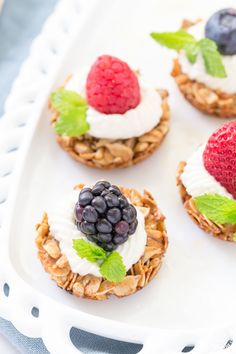 fruit and yogurt on top of granola in a white tray with mint leaves