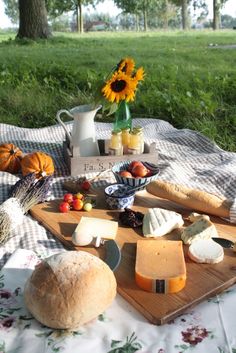 a picnic with bread, cheese and fruit on the table in front of a sunflower