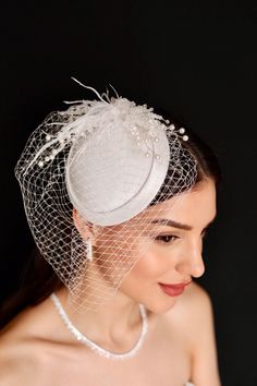 a woman wearing a white veil and headpiece with pearls on the top of it