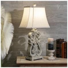 a lamp on a table next to some books and a furnishing material in front of a wood paneled wall