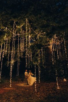 a bride and groom standing under a tree covered in lights