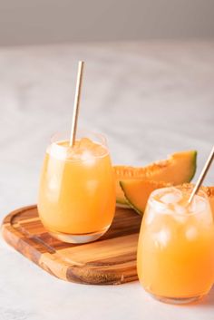 two glasses filled with orange juice and garnished with toothpicks on a cutting board