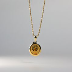 a gold necklace with an image of the virgin mary on it's front and back sides