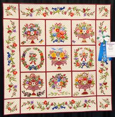 a quilted wall hanging with flowers on it