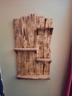 a wooden wall hanging with shelves made out of wood planks and some paint on the walls