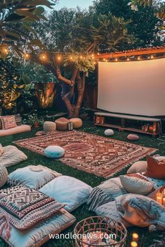 an outdoor movie is set up in the grass with lots of pillows and blankets on it