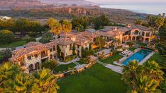 an aerial view of a mansion with a pool in the foreground and mountains in the background