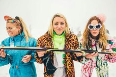 three women standing next to each other holding skis