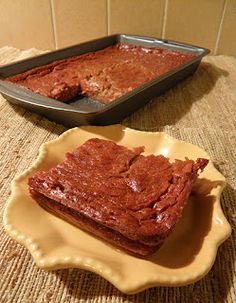 some brownies are sitting on a plate next to a baking pan with one piece cut out