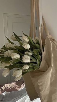 a bouquet of white tulips in a paper bag hanging from a door handle