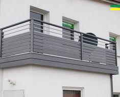 a white building with a metal balcony next to it